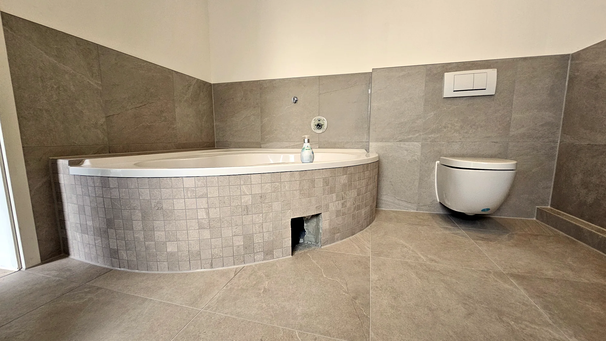 Gerundete Badewanne mit farblich passenden Mosaikfliesen