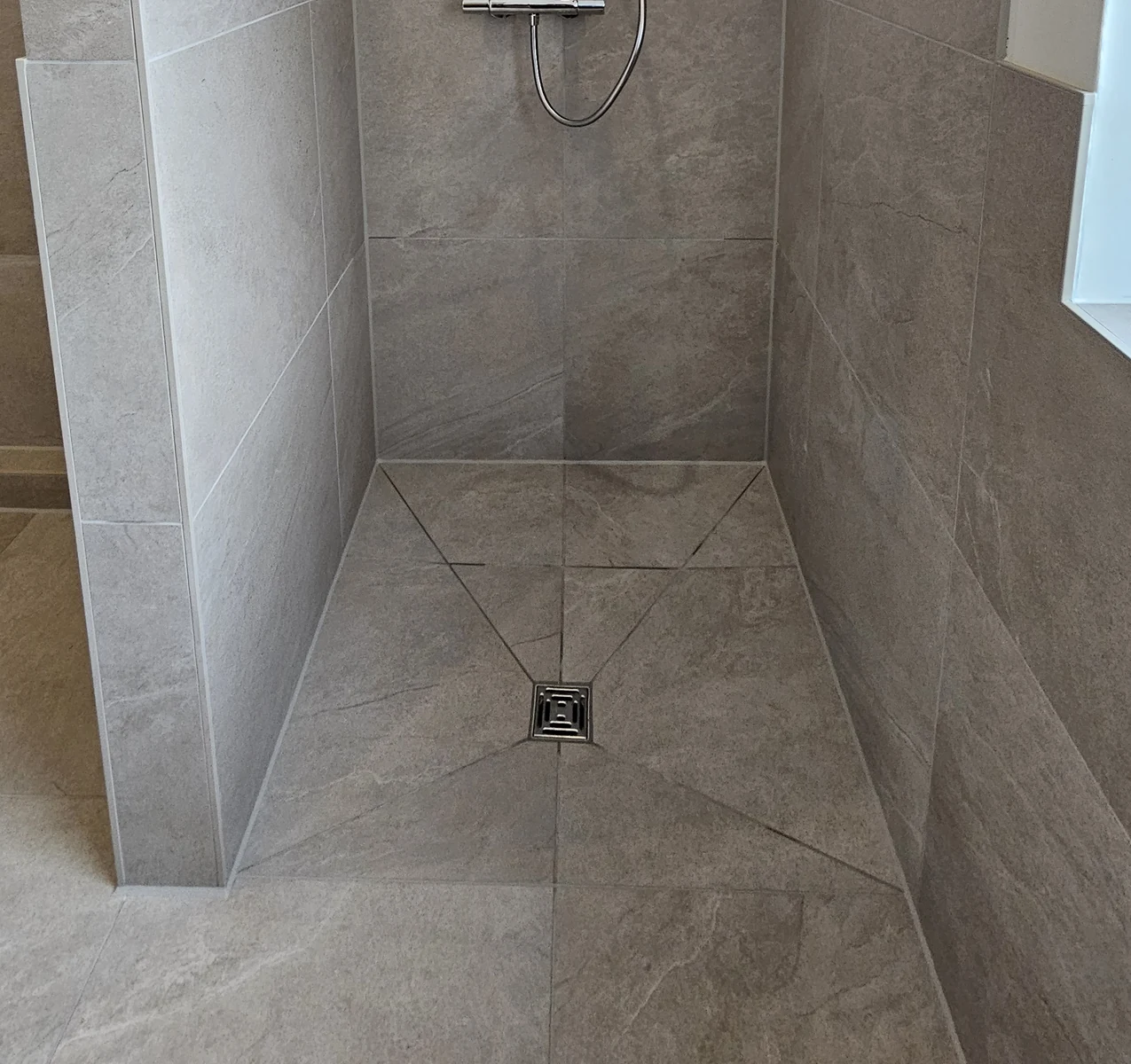 Detail der bodengleichen Dusche mit Punktablauf und diagonalen Fliesenschnitten für das Gefälle